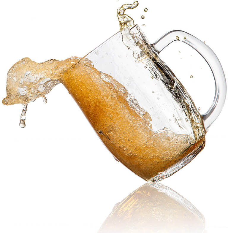 A mug of beer, halfway tipped over and starting to spill.