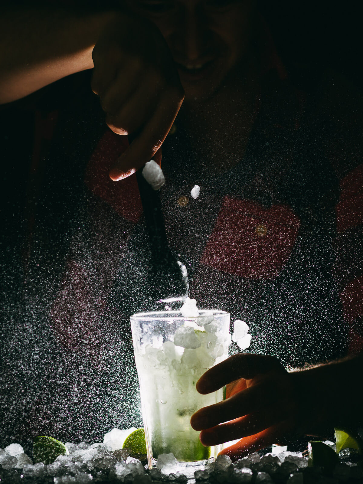 An backlit margarita. An unseen bartender stirs the drink.